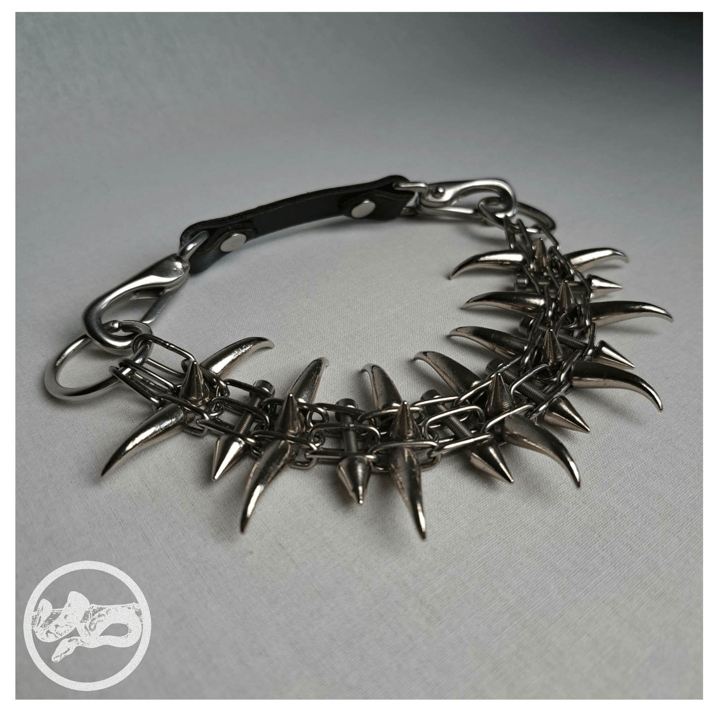 QUERULANT choker necklace made of reclaimed leather and metal hardware, detail shot on table — edgy, handcrafted gothic accessory.