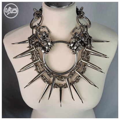 Brutalist necklace FEGEFEUER on a white mannequin, showcasing studded stainless steel chains with long zinc alloy claw spikes, a central O-ring, and a reclaimed leather neckpiece fastened with stainless steel carbines, by skinpressedtight.