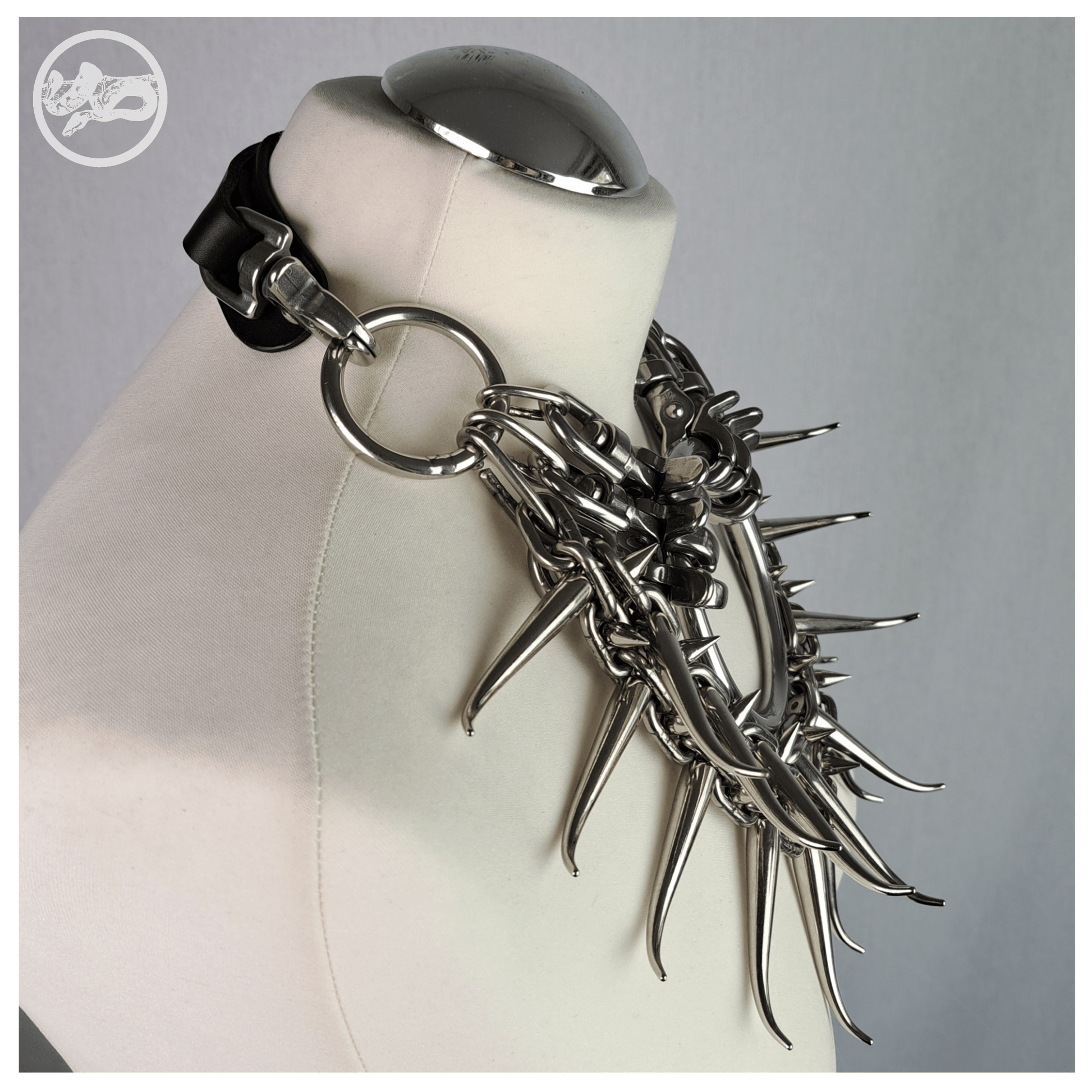 Brutalist necklace FEGEFEUER on a white mannequin, shown from the side to highlight the layered studded chains, long zinc alloy claw spikes, and the reclaimed leather neckpiece connected by stainless steel carbines, by skinpressedtight.