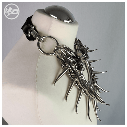 Brutalist necklace FEGEFEUER on a white mannequin, shown from the side to highlight the layered studded chains, long zinc alloy claw spikes, and the reclaimed leather neckpiece connected by stainless steel carbines, by skinpressedtight.