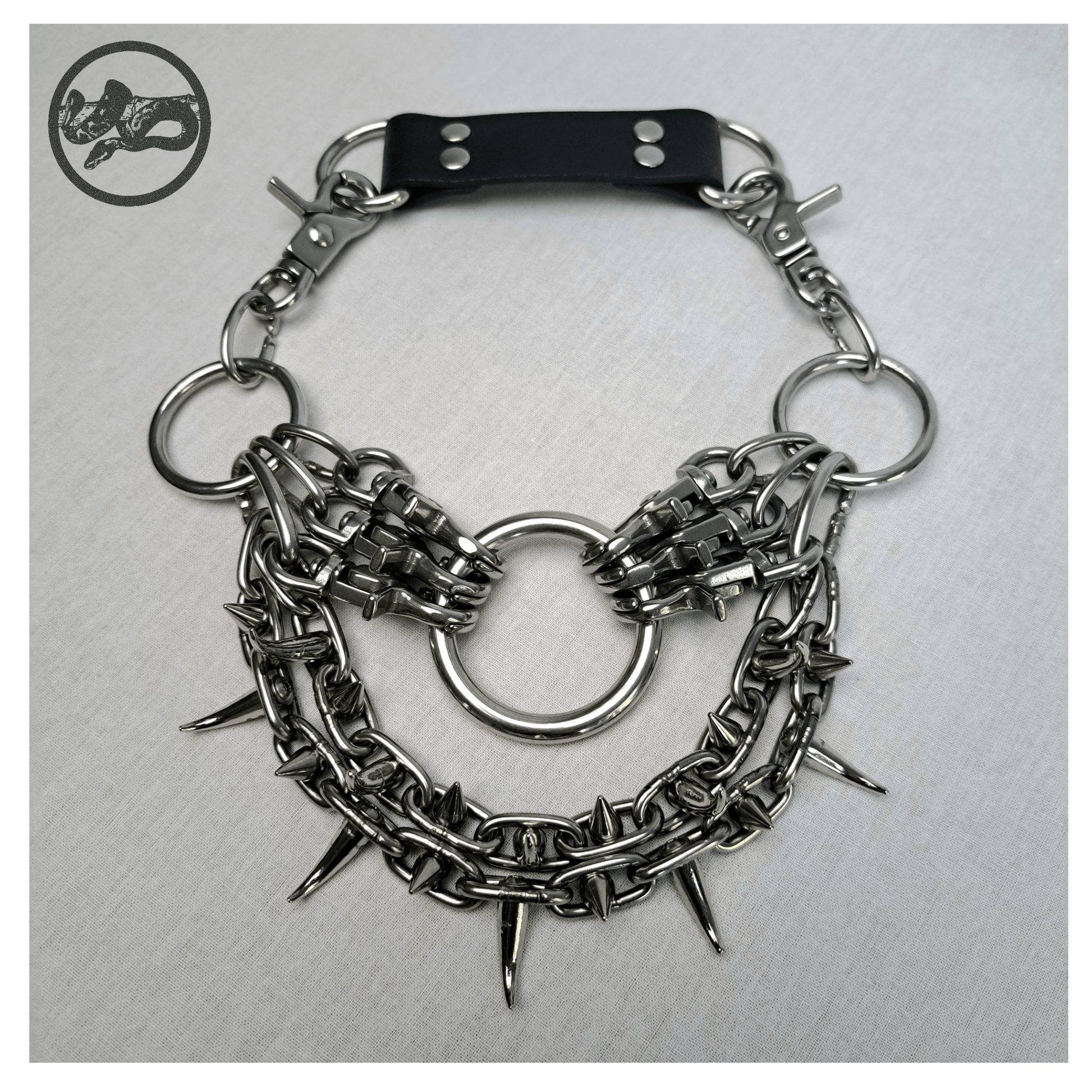 ChatGPT said:

FEGEFLAMME brutalist necklace laid out on a white background, front view showing studded stainless steel chains with small zinc alloy claw spikes, central O-ring, and reclaimed leather neckpiece secured with stainless steel carbines — gothic handcrafted accessory by skinpressedtight.