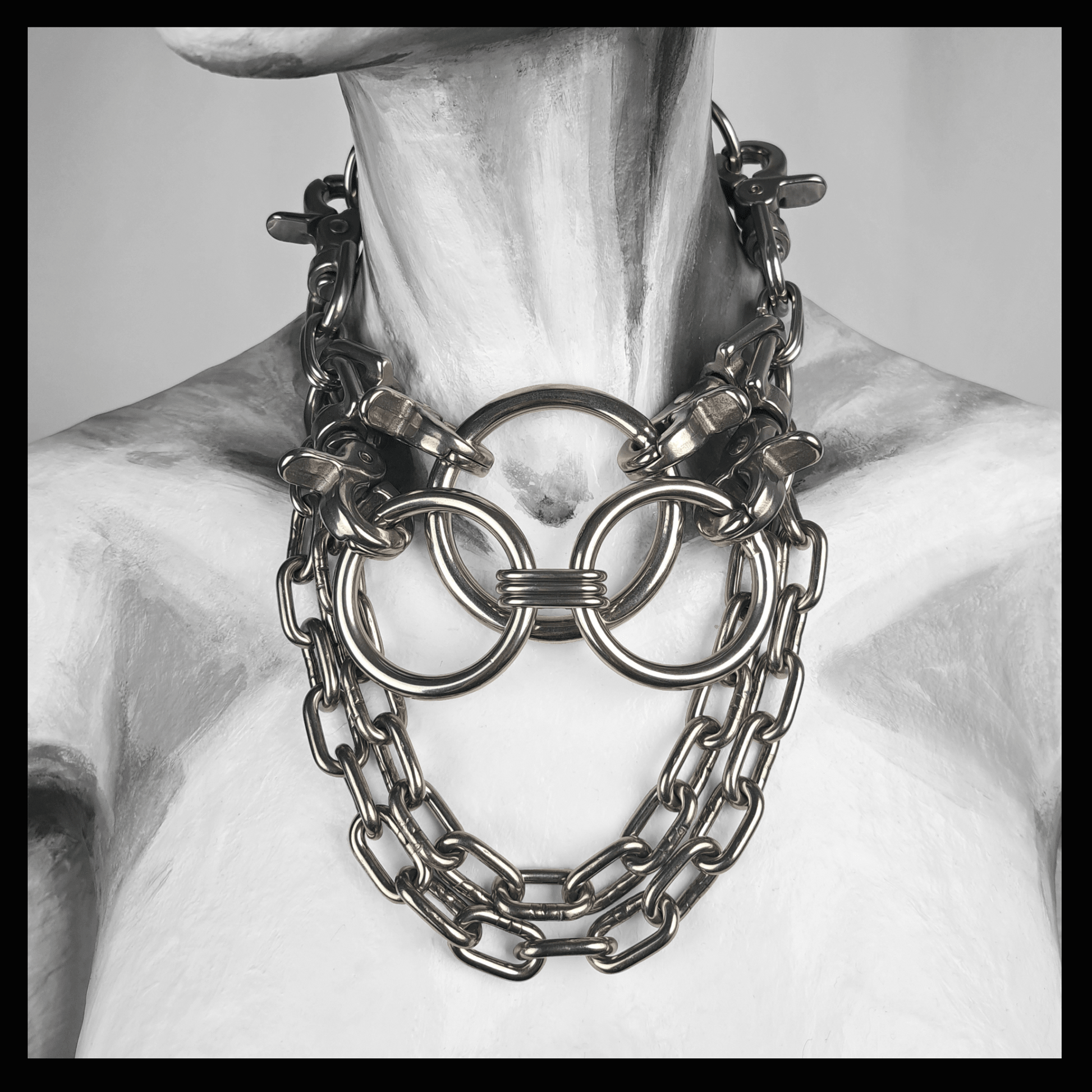 FLAECHENBRAND brutalist necklace featuring layered stainless steel rings clasped by carbines, flanked by chains, and a detachable reclaimed leather neckpiece — displayed on white mannequin, handcrafted by skinpressedtight