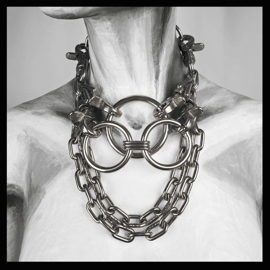 FLAECHENBRAND brutalist necklace featuring layered stainless steel rings clasped by carbines, flanked by chains, and a detachable reclaimed leather neckpiece — displayed on white mannequin, handcrafted by skinpressedtight