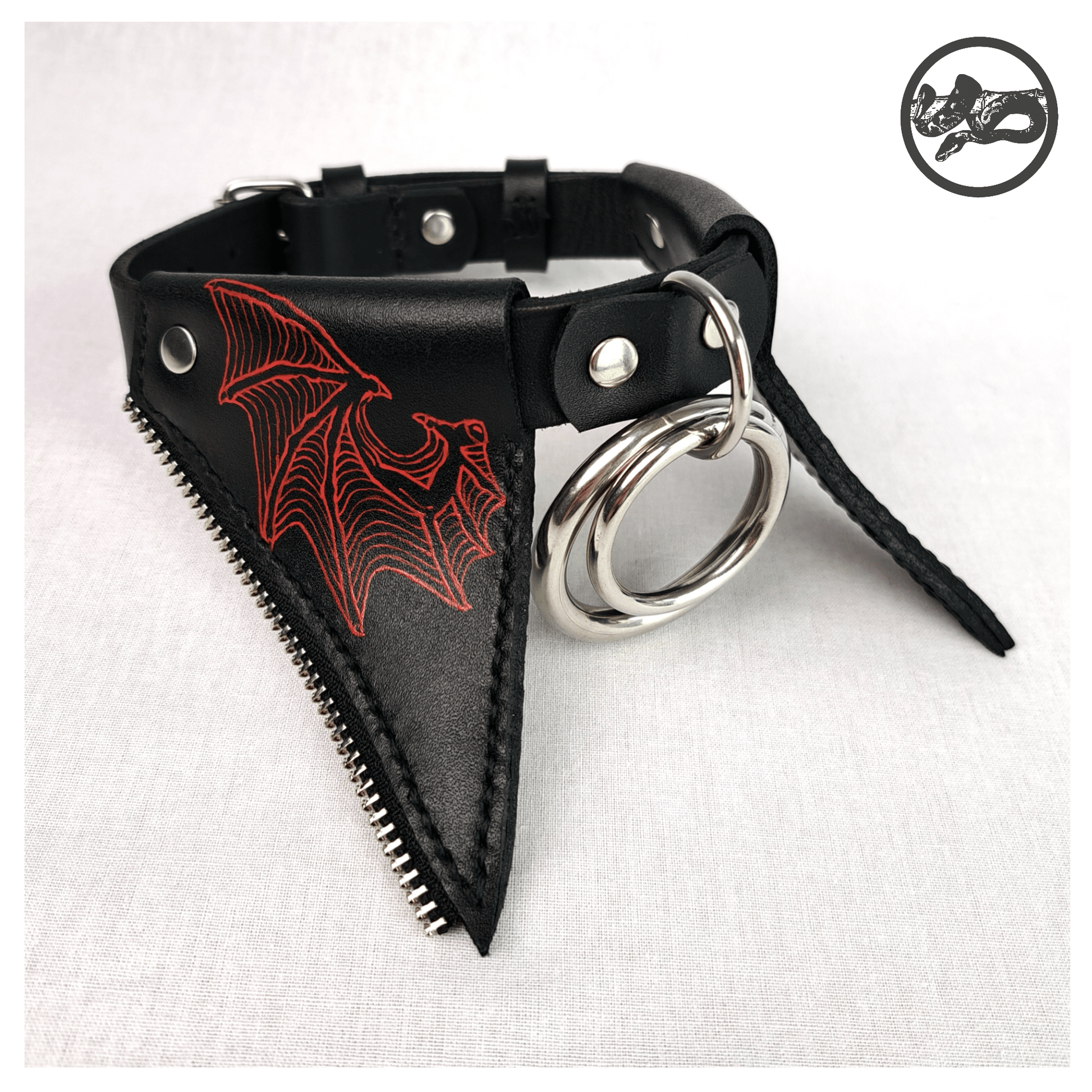 FLEDERTIER – SABBATH choker necklace laid out on a white background, showing the front view of the black leather design with stainless steel and zinc alloy hardware and vivid handpainted red bat wing ornaments, by skinpressedtight.