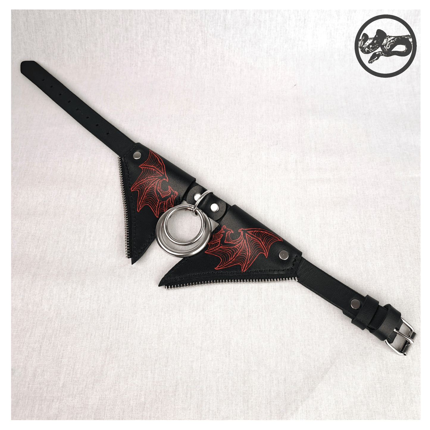 FLEDERTIER – SABBATH choker necklace laid out opened up on a white background, showing the front view of the black leather design with stainless steel and zinc alloy hardware and striking handpainted red bat wing ornaments, by skinpressedtight.