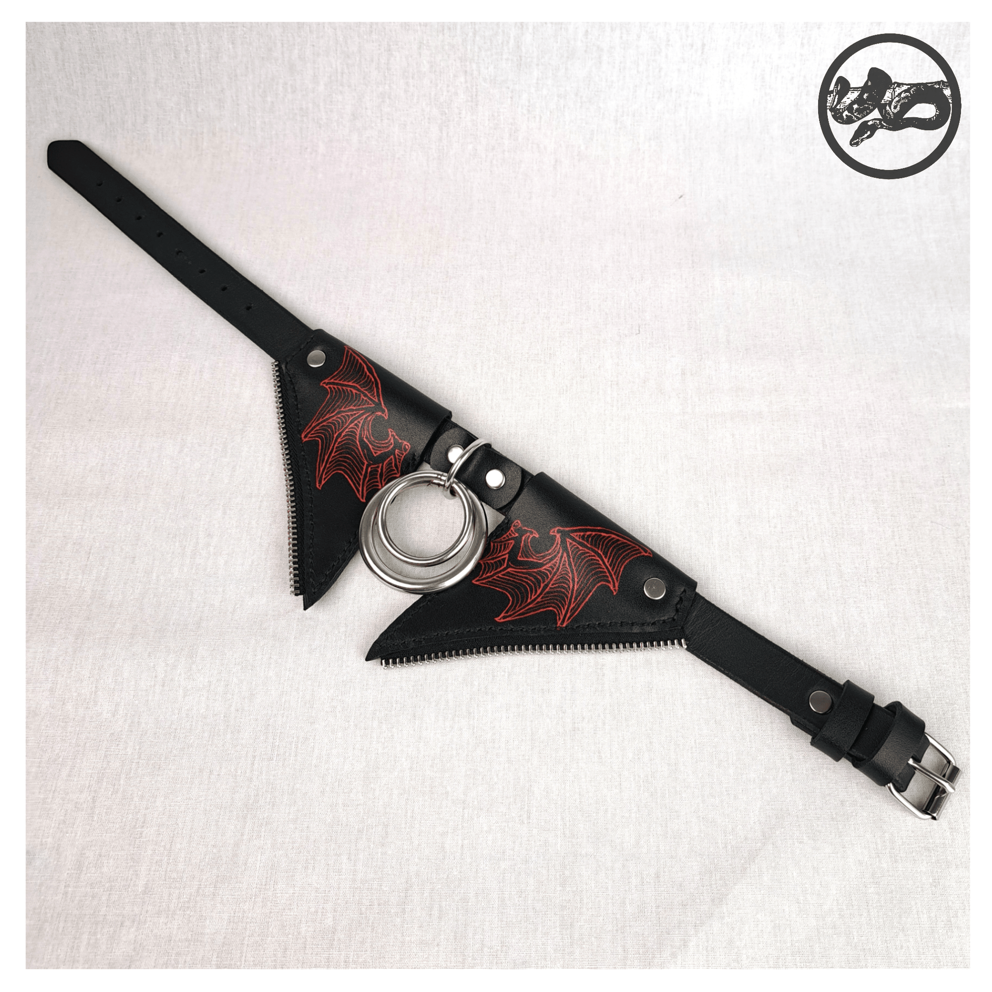 FLEDERTIER – SABBATH choker necklace laid out opened up on a white background, showing the front view of the black leather design with stainless steel and zinc alloy hardware and striking handpainted red bat wing ornaments, by skinpressedtight.
