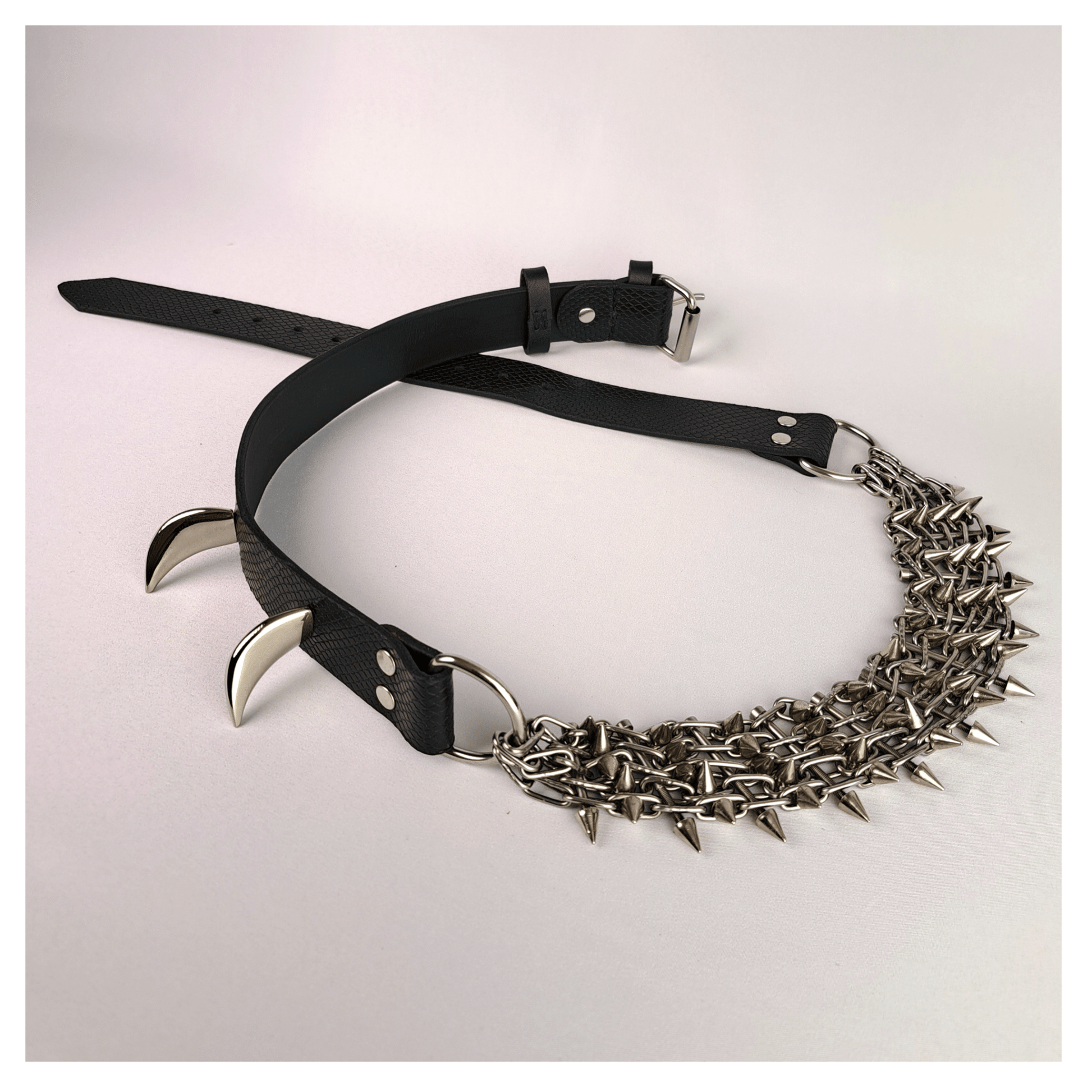 KLINGENSÄNGER — VIPER edition belt laid out on white background, featuring black viper print leather, metal chainspike hardware, and prominent fang studs — handcrafted gothic statement piece by skinpressedtight