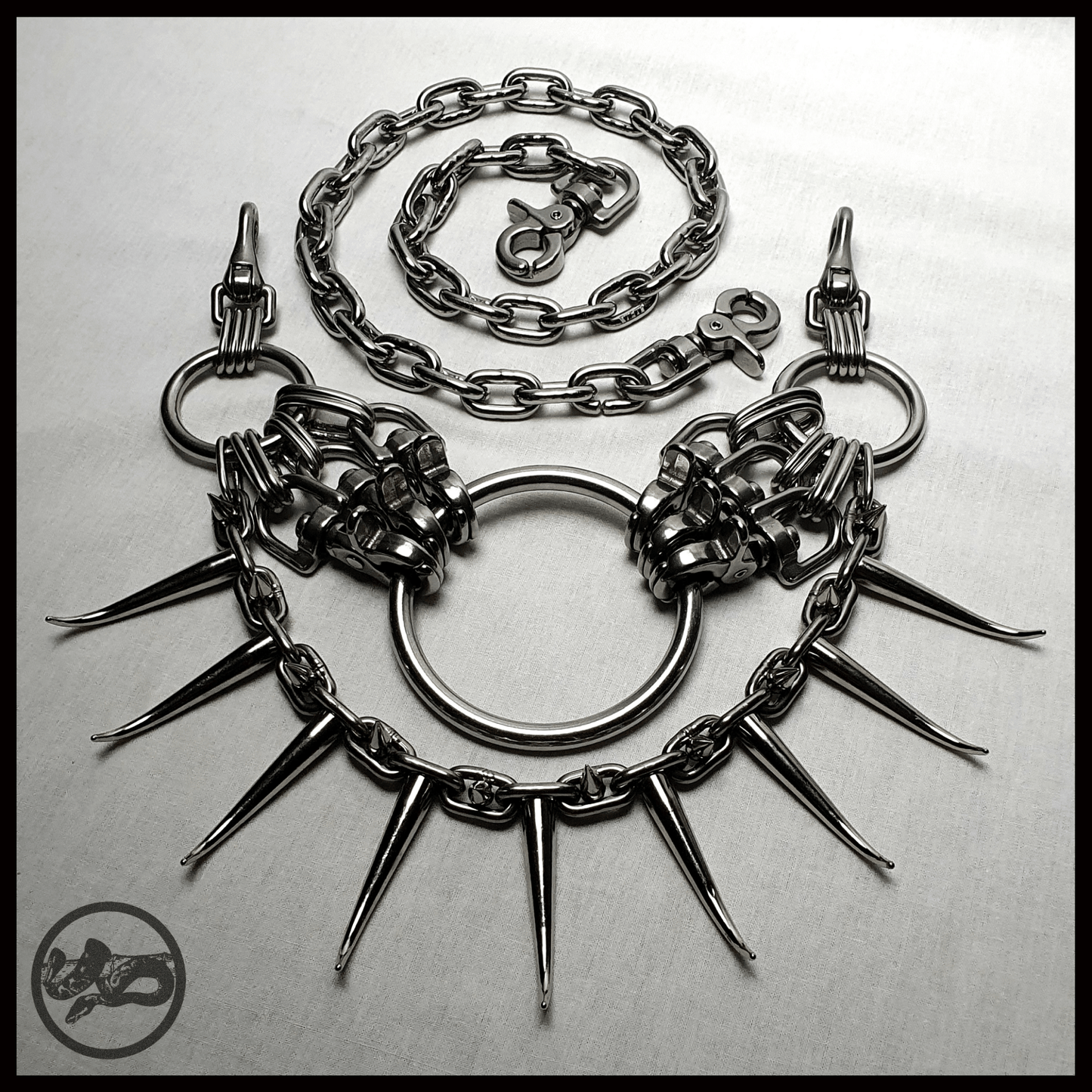 MYRAPOD - SPINNENLÄUFER belt in brutalist design with spiked chain, handcrafted from stainless steel. This edition is extended with a chunky chain, spiked with huge zinc alloys claw studs — shown shown laid out on table, alternative statement piece by skinpressedtight