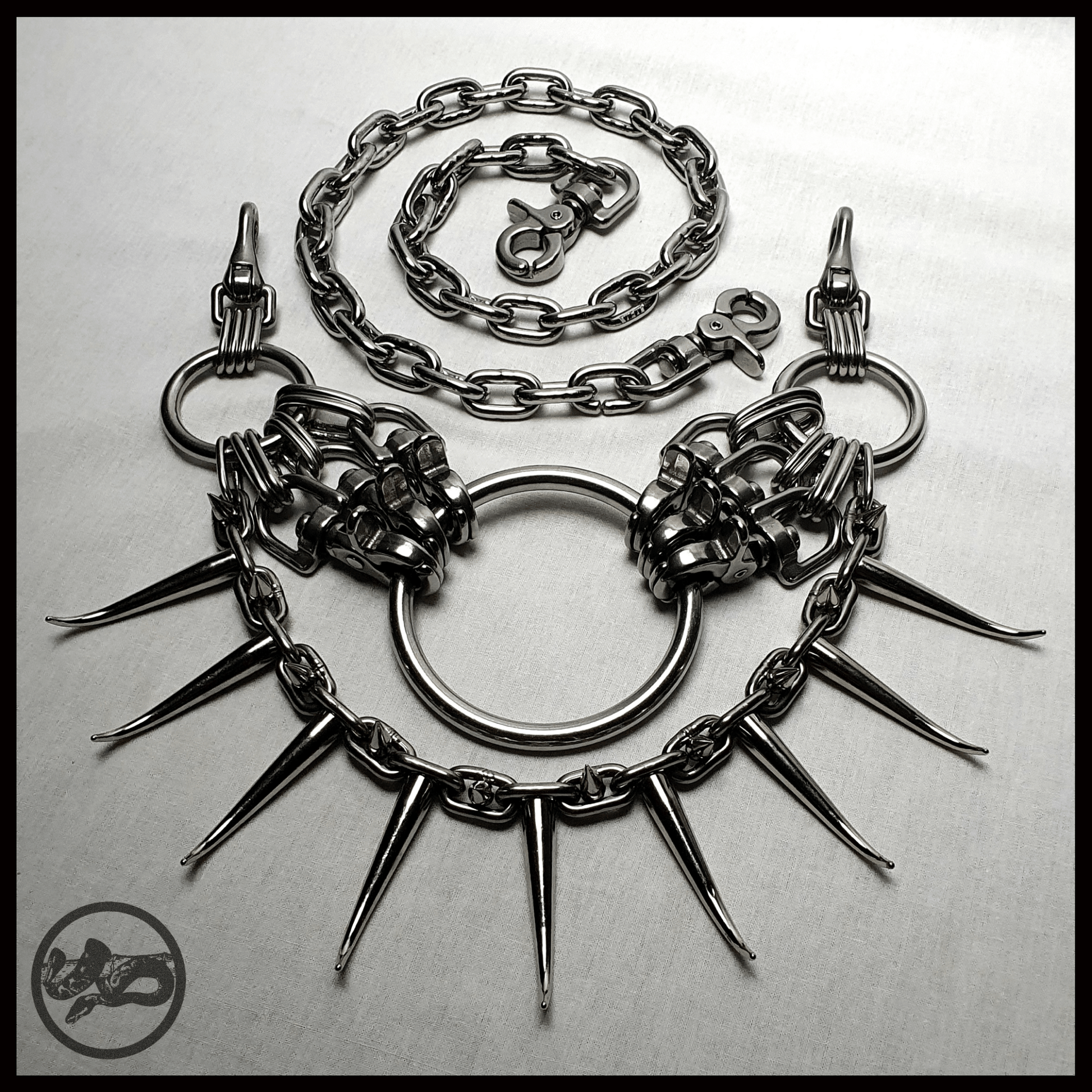 MYRAPOD - SPINNENLÄUFER belt in brutalist design with spiked chain, handcrafted from stainless steel. This edition is extended with a chunky chain, spiked with huge zinc alloys claw studs — shown shown laid out on table, alternative statement piece by skinpressedtight