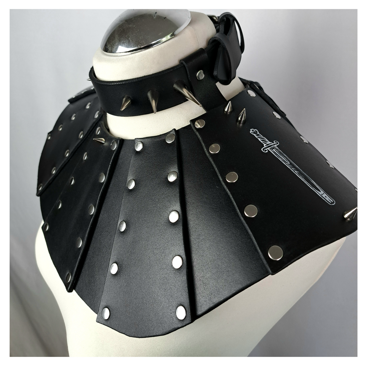 BLUTSPUR leather gorget from the side on a dress form: riveted black leather panels over the shoulder and the spiked collar at the neck. Handmade by skinpressedtight