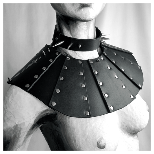BLUTSPUR leather gorget worn on a painted mannequin: fanned black leather panels edged with rows of silver rivets over the shoulders, a spiked leather neck strap above. Handmade by skinpressedtight