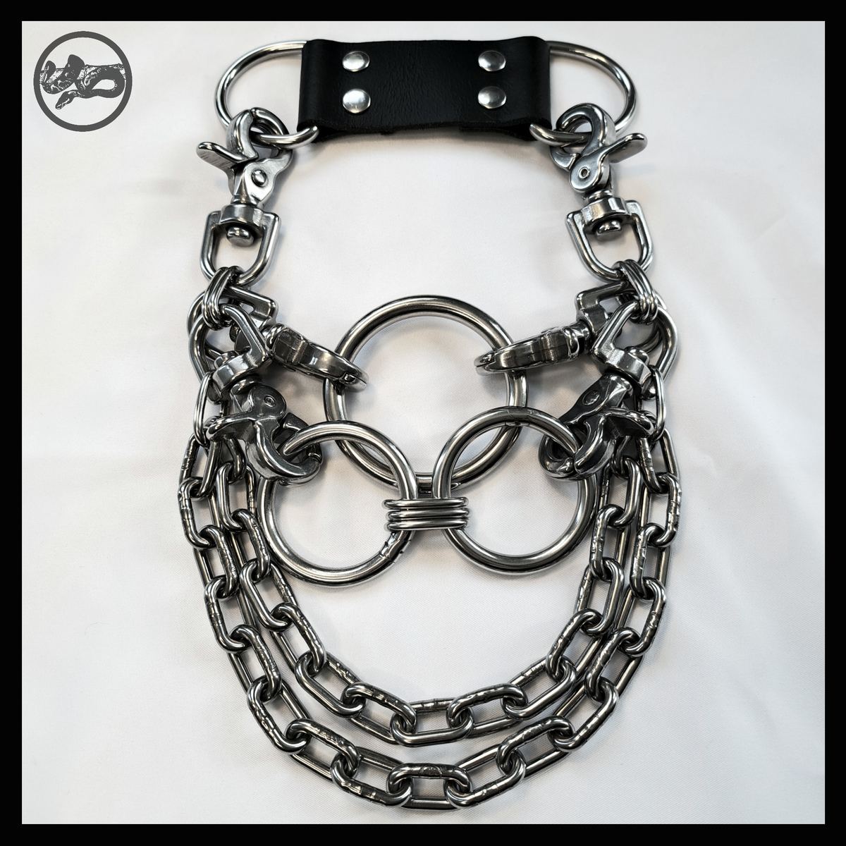 FLĀCHENBRAND statement necklace laid flat: a formation of three big stainless O-rings, polished scissor carabiners, two swags of thick chain and a black leather neckpiece with D-rings. Handmade by skinpressedtight