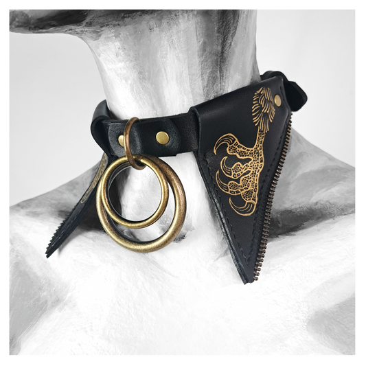 FLEDERTIER – BABA JAGA leather choker worn on a painted mannequin: tall pointed black leather wing flaps hand-painted with gold chicken feet, a nested brass double ring at the throat. Handmade by skinpressedtight