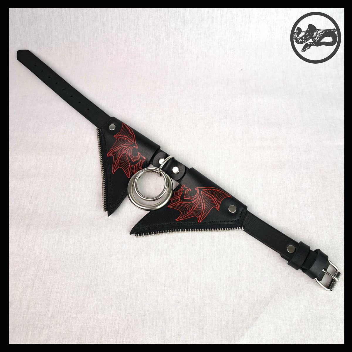 FLEDERTIER – SABBATH leather choker laid out open: the red-painted wing flaps, stainless double ring and the black strap with a roller buckle. Handmade by skinpressedtight