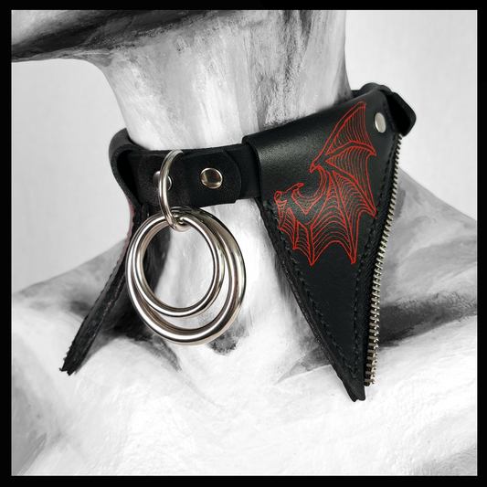FLEDERTIER – SABBATH leather choker worn on a painted mannequin: tall pointed black leather wing flaps hand-painted in fiery red, a stainless double ring at the throat. Handmade by skinpressedtight