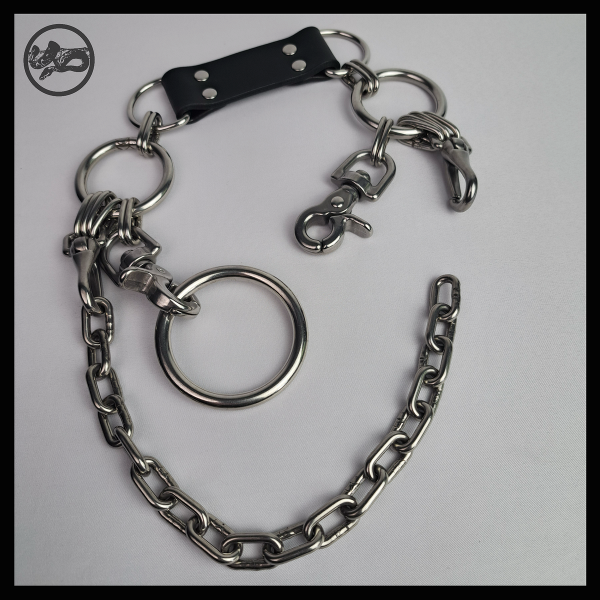FROSTGLANZ chain necklace open, laid flat: black leather neckpiece with D-rings, one stainless rein hook unclipped, the large O-ring and the chain swag below. Handmade by skinpressedtight