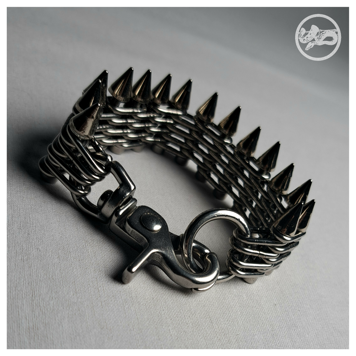 GEWALTBEREIT spiked chain bracelet closed, showing the clasp: a polished scissor snap hook clipped into a small stainless O-ring at the end of the chain band. Handmade by skinpressedtight
