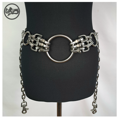 MYRAPOD chain belt on a black dress form, front: large central O-ring, clusters of polished scissor carabiners on each side, chain ends with rein hooks hanging at the hips. Handmade by skinpressedtight