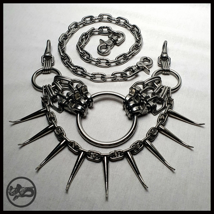 MYRAPOD – SPINNENLĀUFER spiked chain belt laid out flat: central O-ring, scissor carabiner clusters, a chain swag of curved horn spikes and small cone spikes, waist chain coiled above. Handmade by skinpressedtight