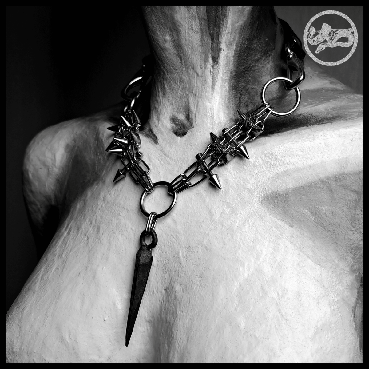SARGNAGEL spiked chain necklace worn, front view, black and white: a V of fine stainless chain bristling with cone spikes, the forged coffin nail hanging from the centre ring. Handmade by skinpressedtight