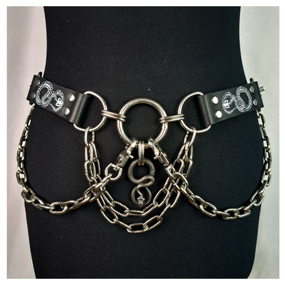 VIPERNZIRKEL – BONES chain belt on a black dress form, front: white snake skeletons on the leather tabs, steel O-rings, chain swags and a silver snake pendant. Handmade by skinpressedtight